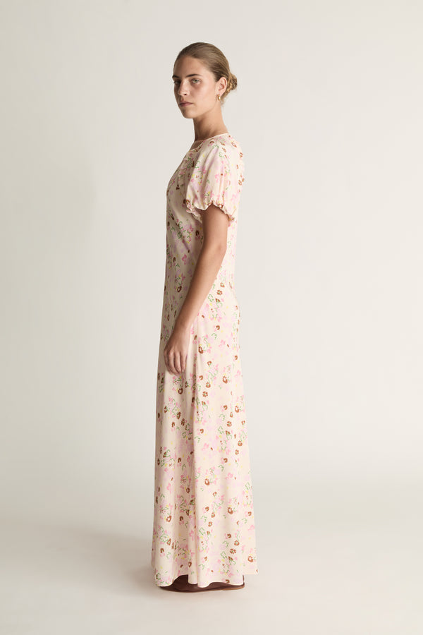 Woman wearing a long floral dress on a plain background