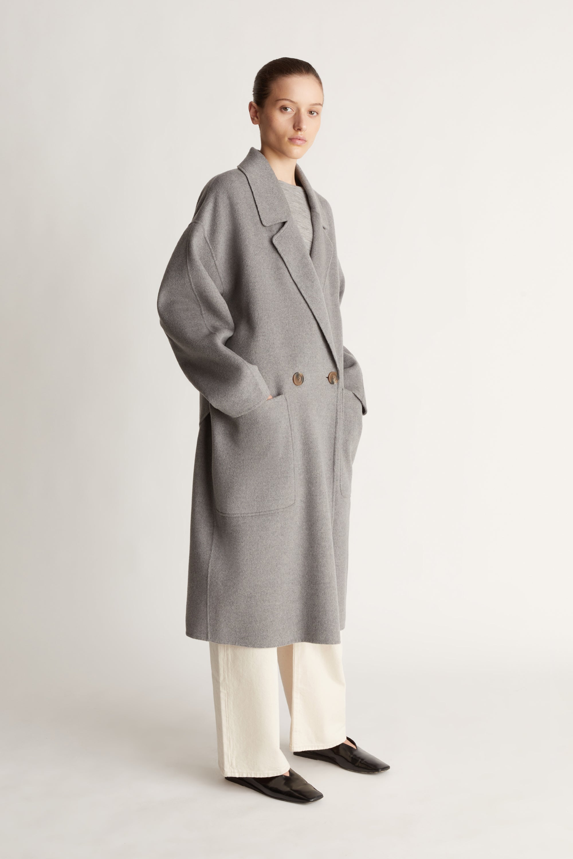 Person wearing a gray coat on a plain background