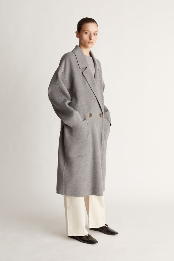 Person wearing a gray coat on a plain background