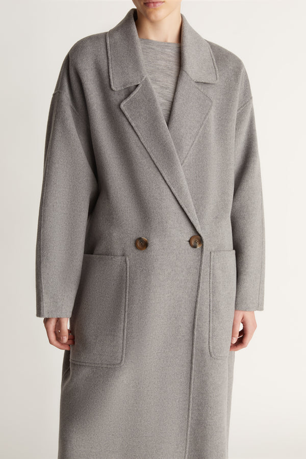 Person wearing a gray coat on a plain background