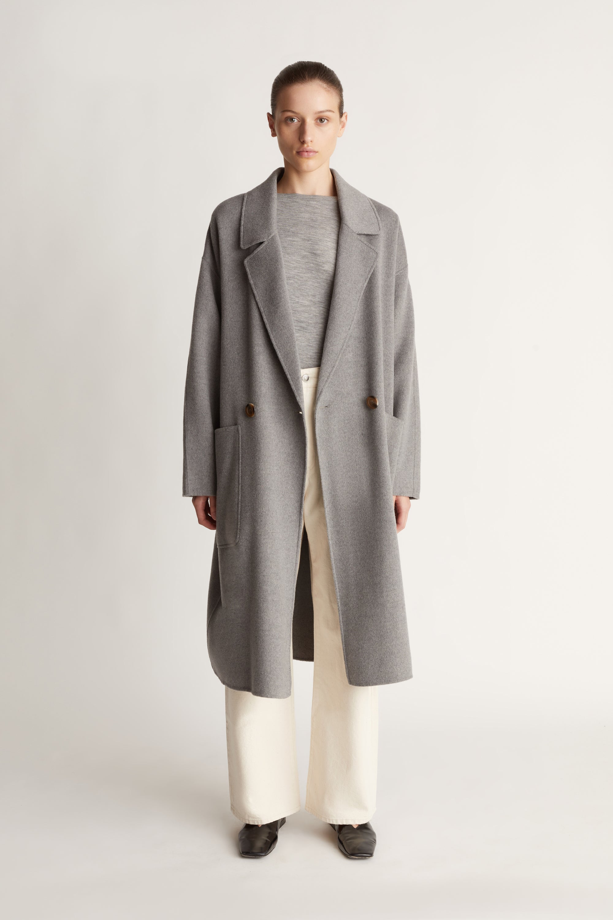 Person wearing a gray coat on a plain background