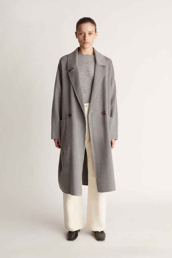 Person wearing a gray coat on a plain background