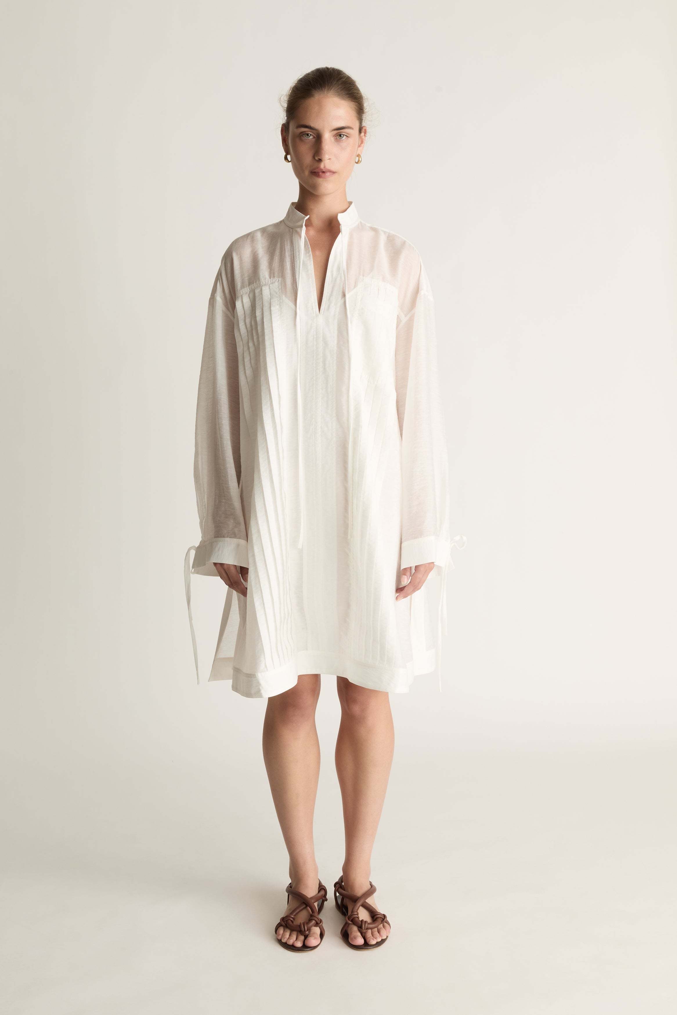 Woman wearing a white tunic against a plain background