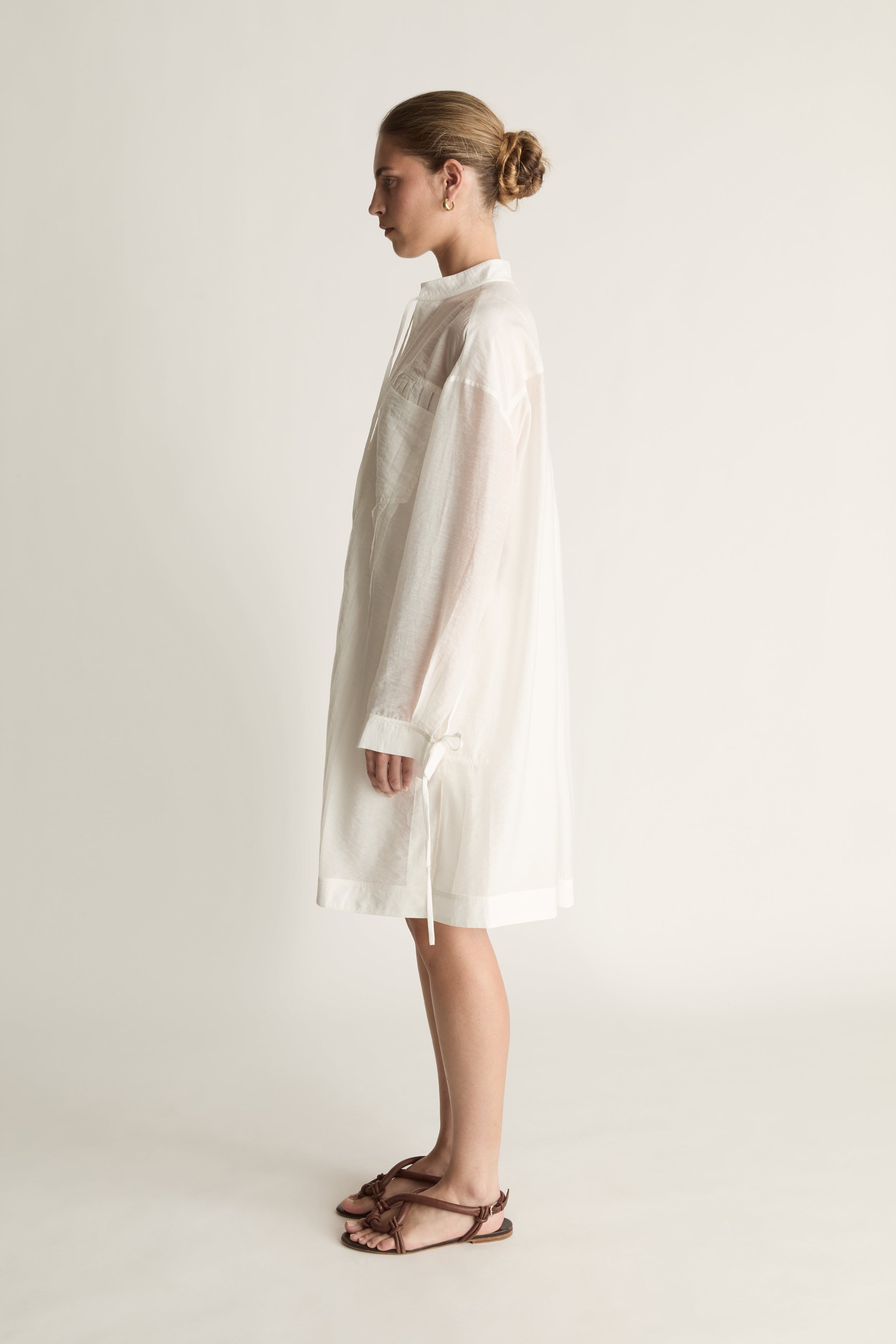 Woman wearing a white tunic against a plain background