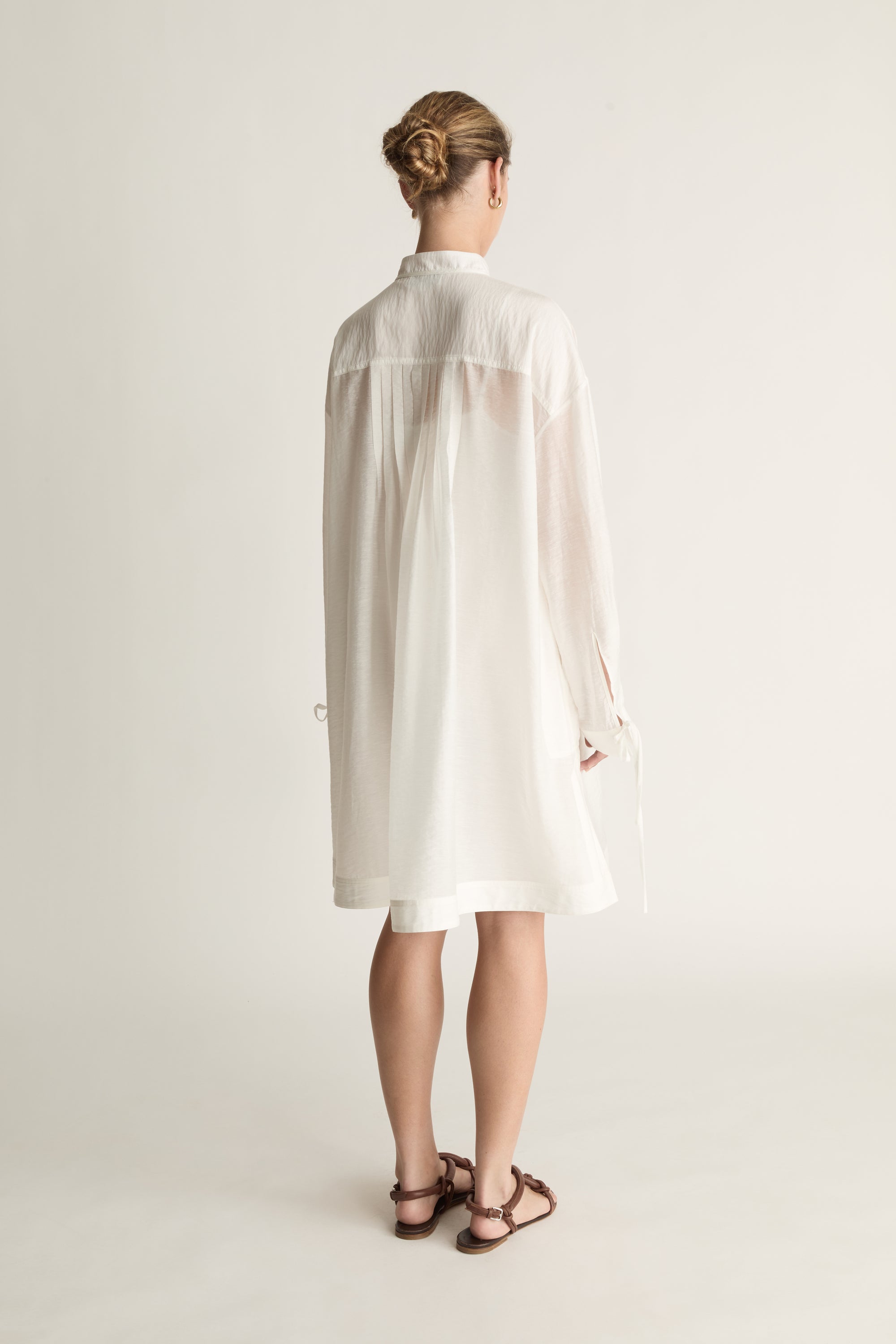 Woman wearing a white tunic against a plain background