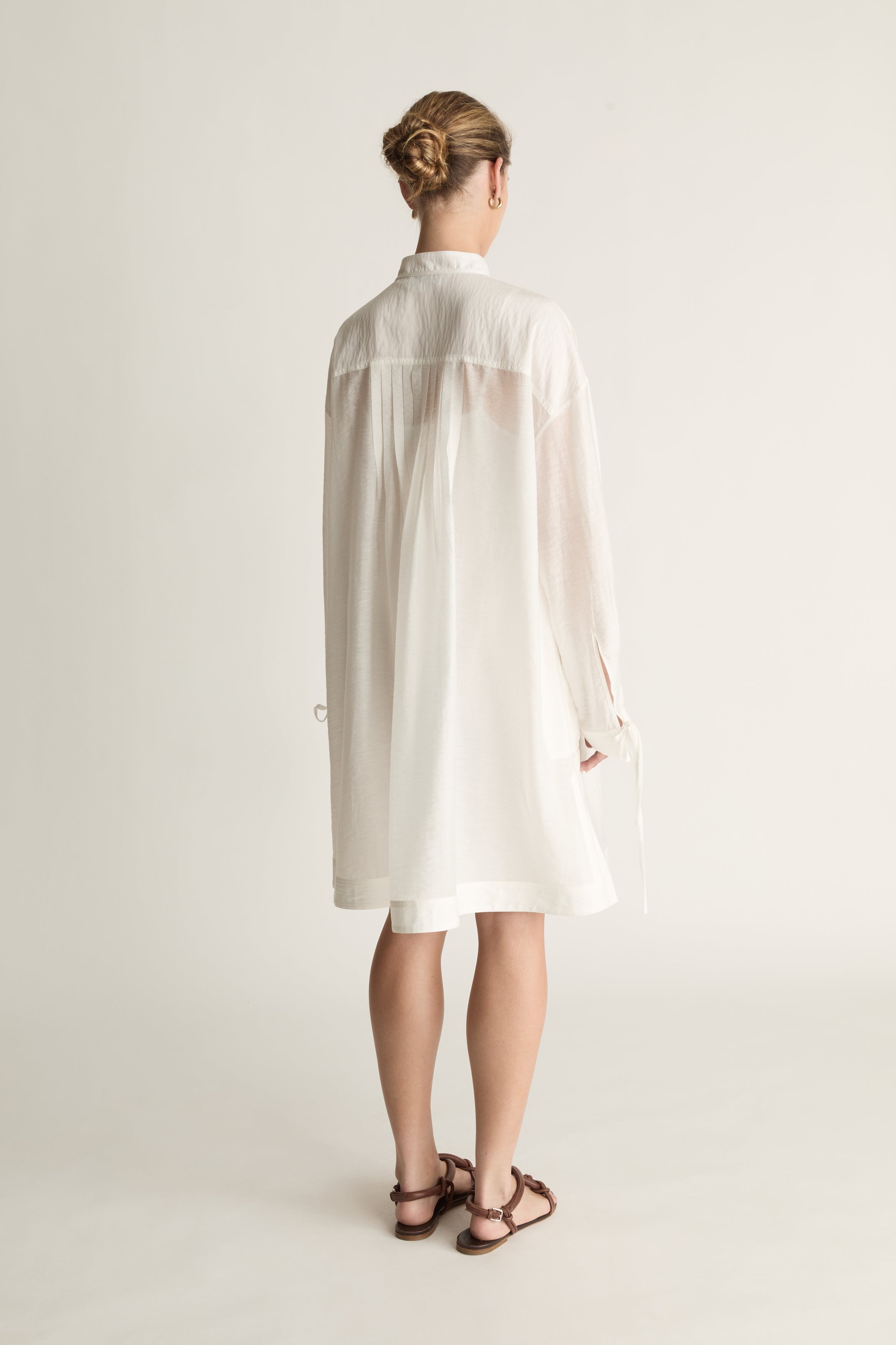 Woman wearing a white tunic against a plain background