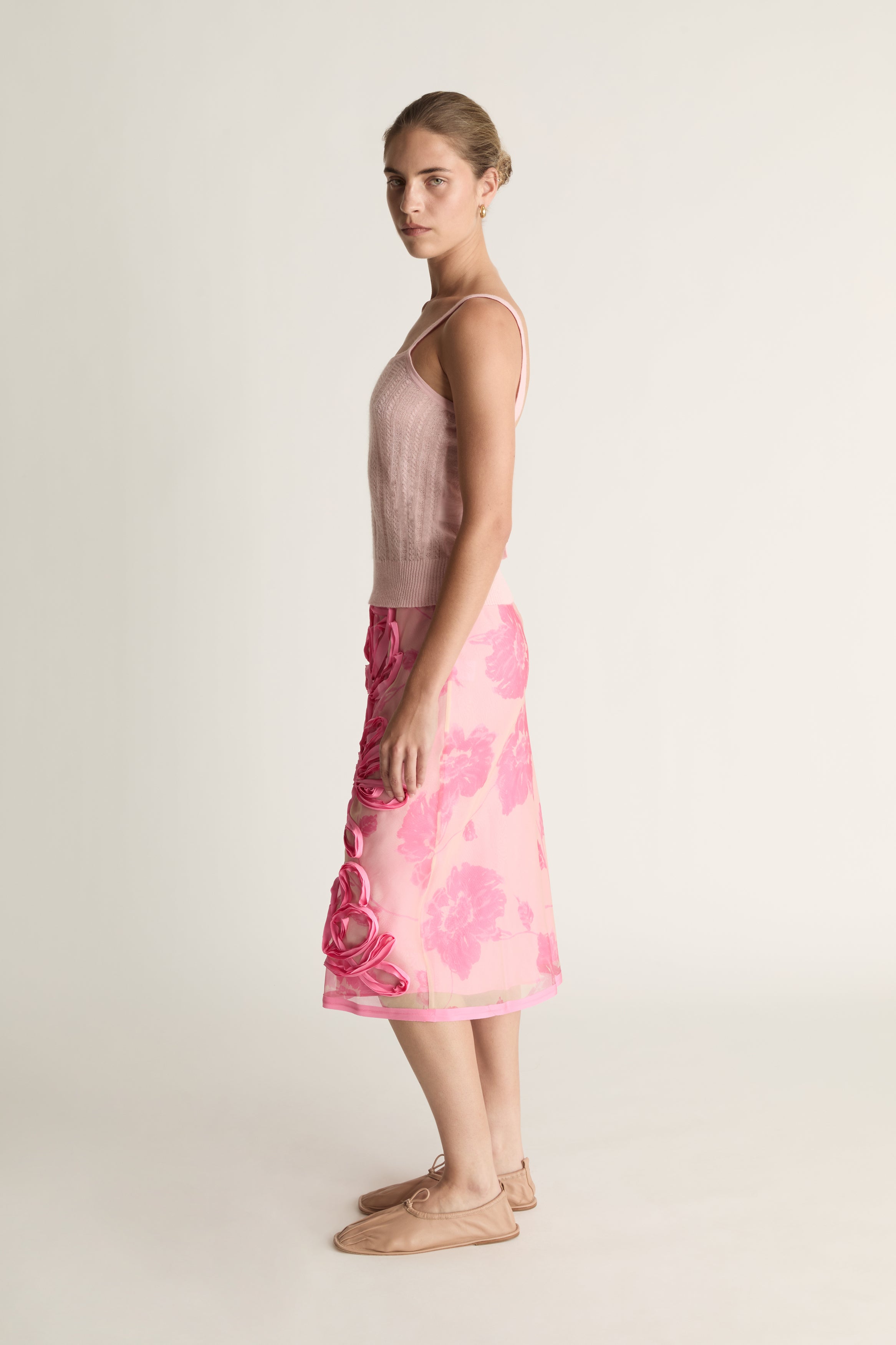 Woman wearing a pink floral dress on a plain background