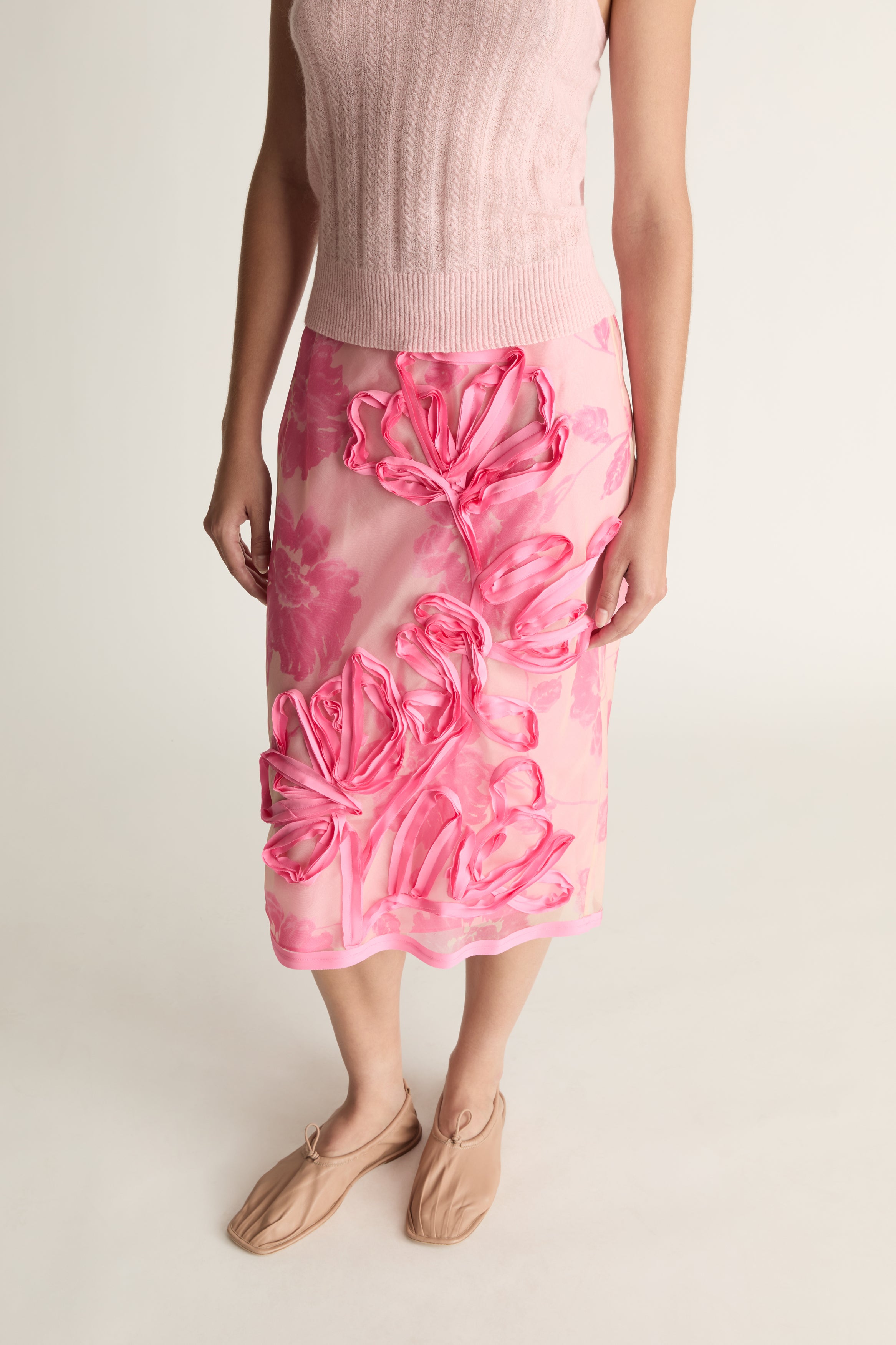 Person wearing a pink floral skirt on a plain background