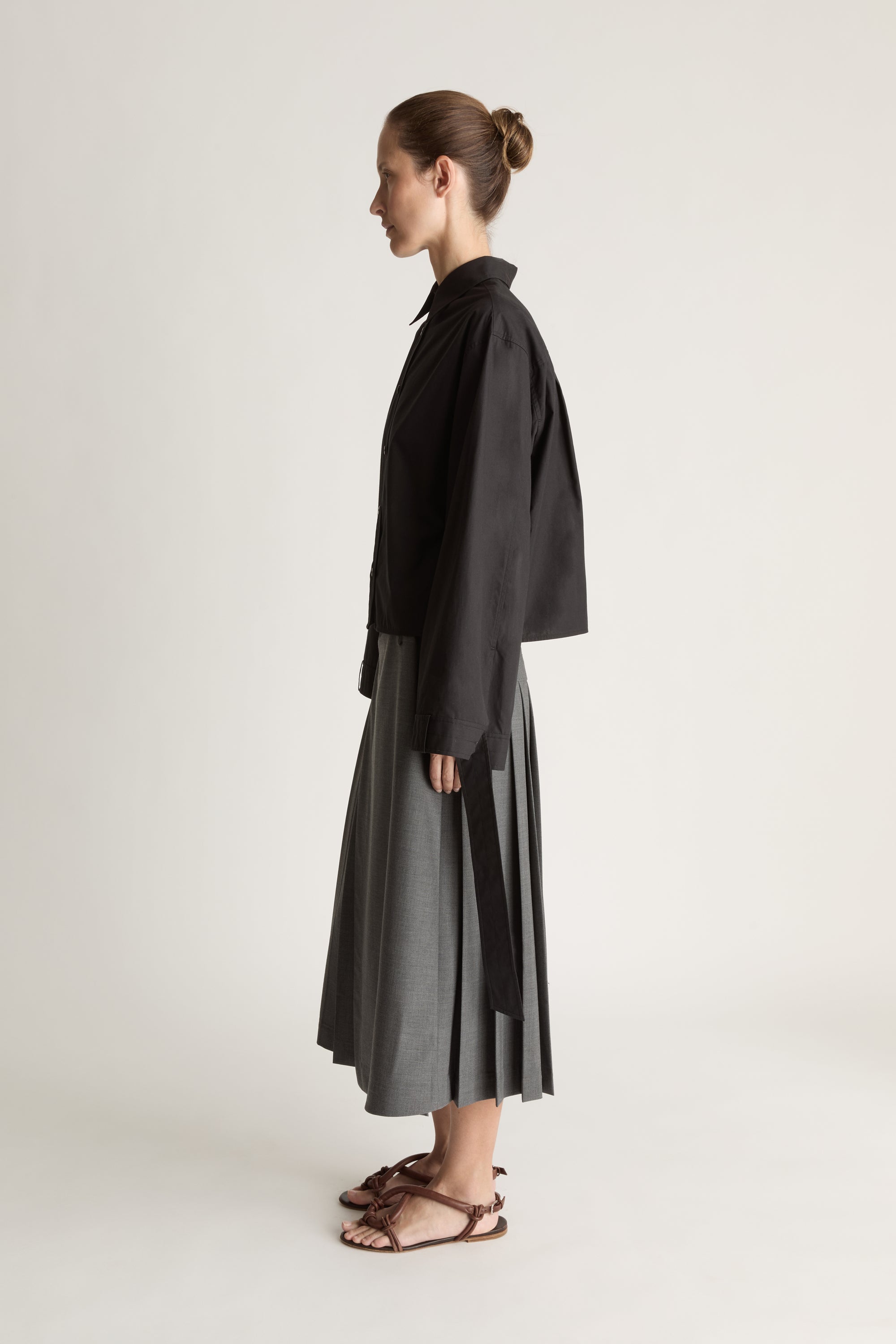 Person wearing a black shirt and gray skirt on a white background