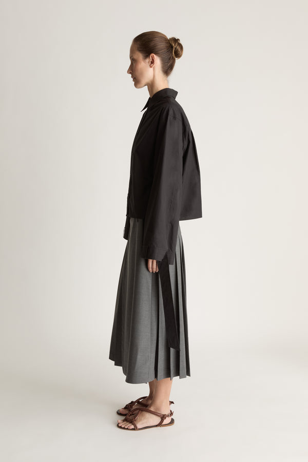 Person wearing a black shirt and gray skirt on a white background