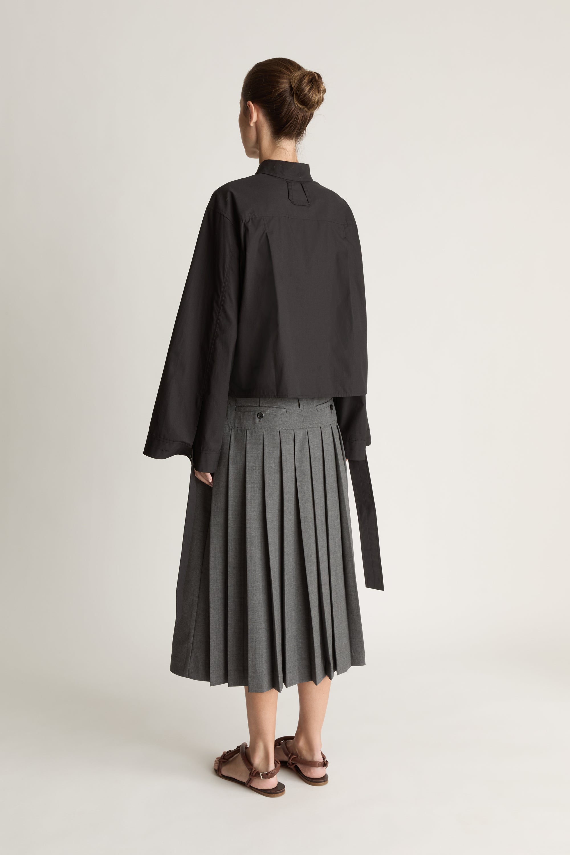 Person wearing a black shirt and gray skirt on a white background