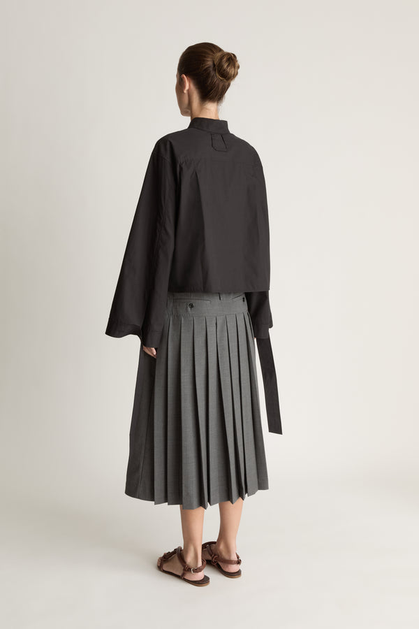 Person wearing a black shirt and gray skirt on a white background