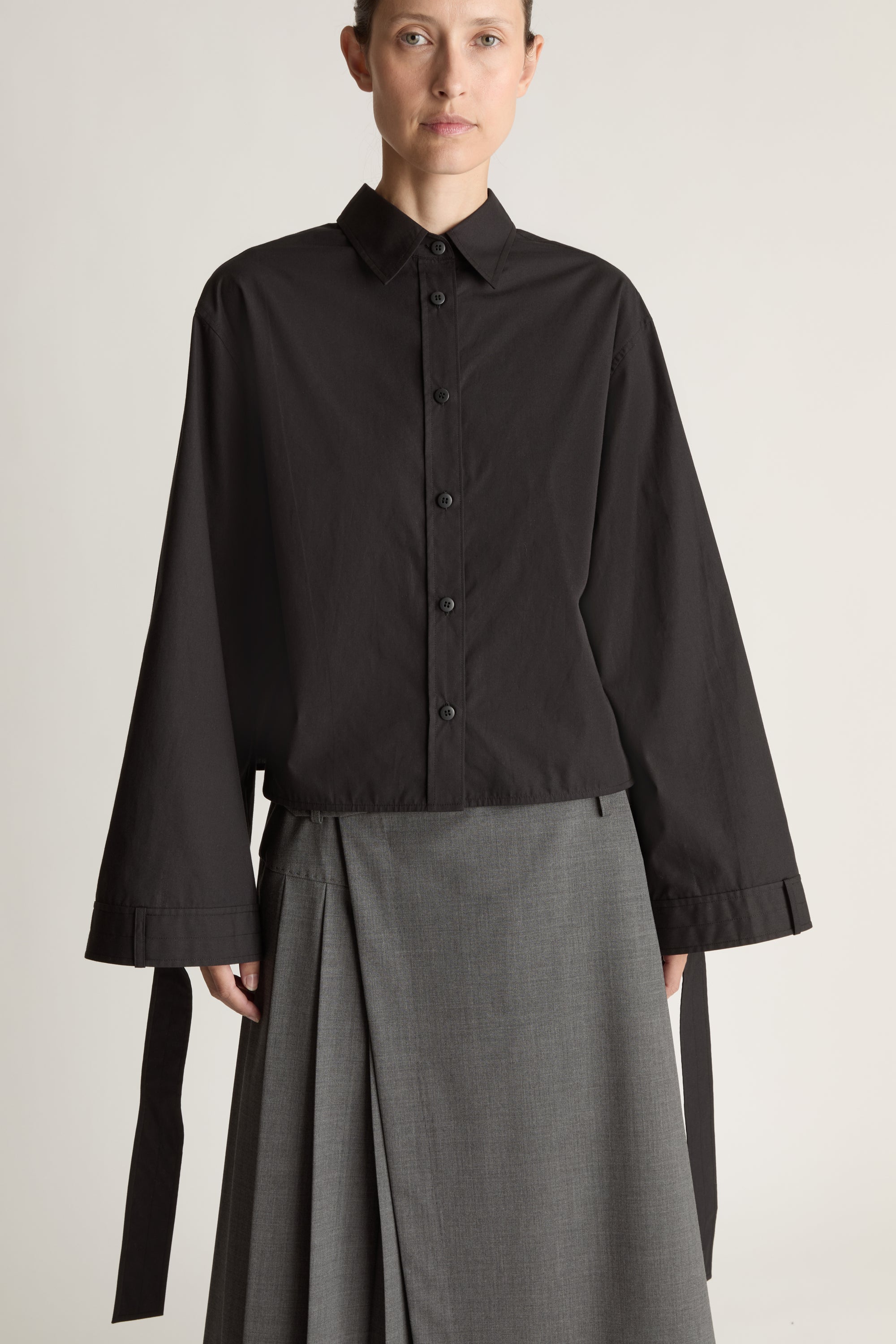 Person wearing a black shirt and gray skirt on a white background