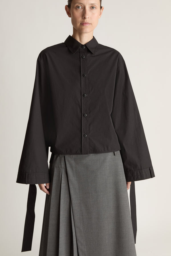 Person wearing a black shirt and gray skirt on a white background