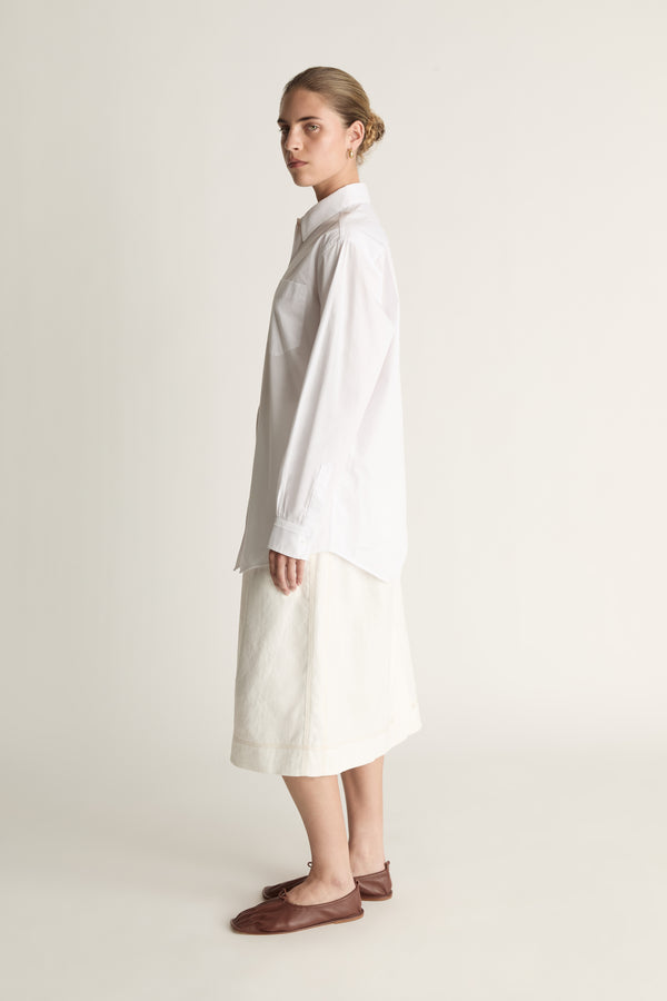 Person wearing a long white shirt and skirt on a plain background