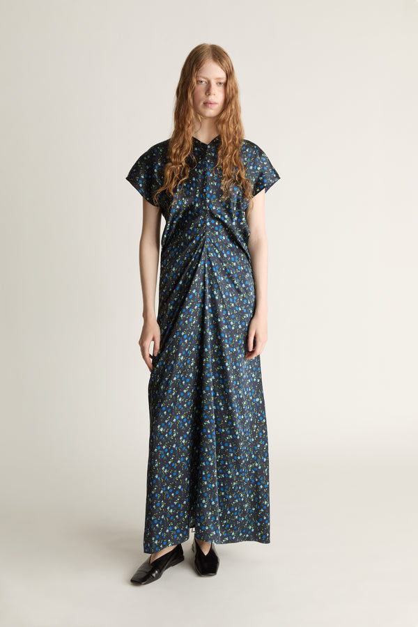 Woman wearing a long, patterned blue dress on a plain background