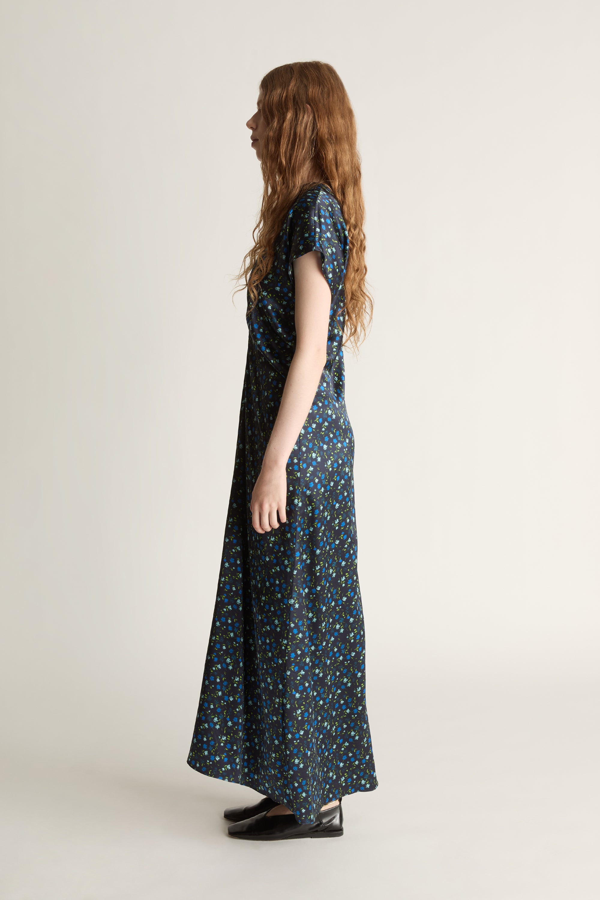 Woman wearing a long, patterned blue dress on a plain background