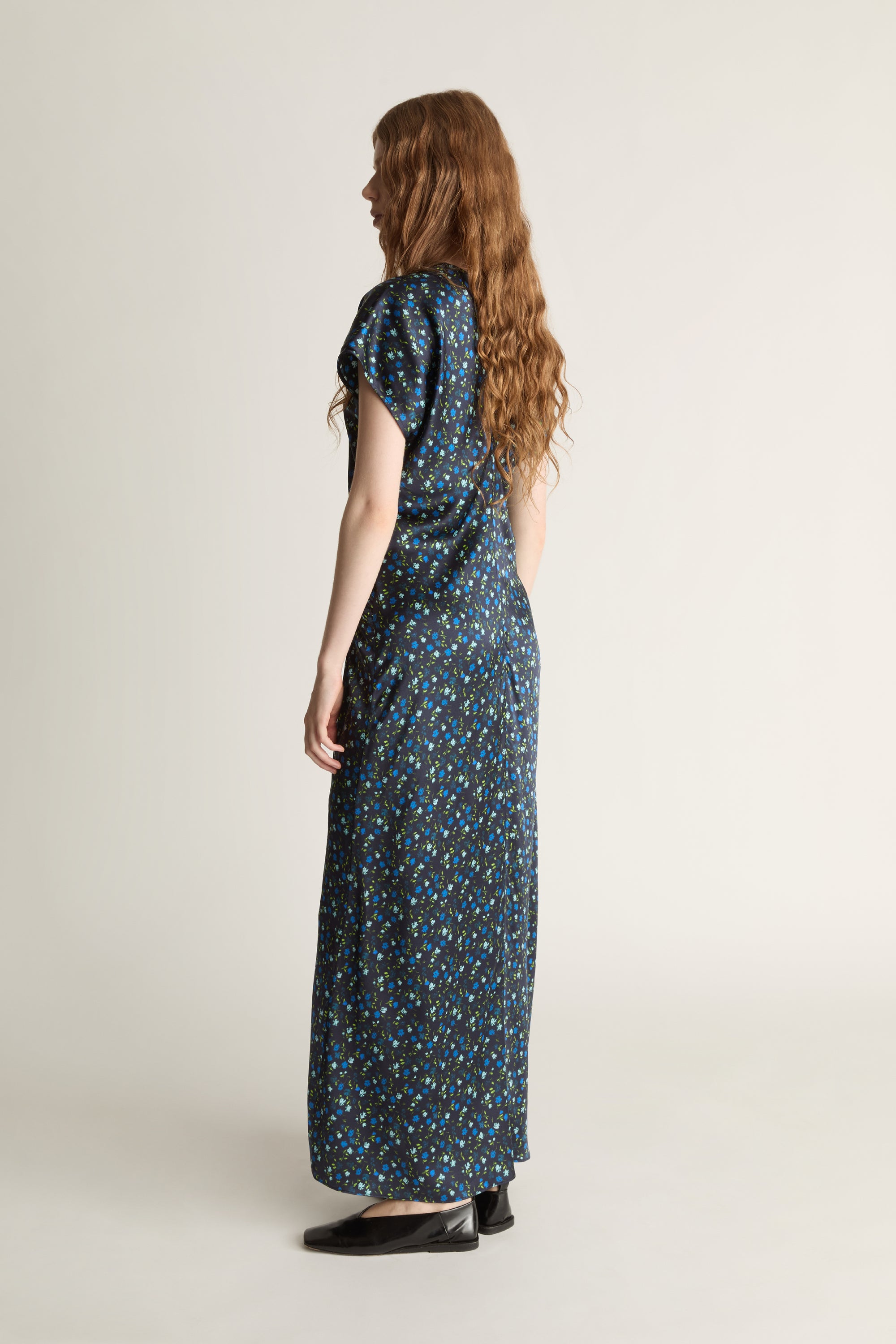 Woman wearing a long, patterned blue dress on a plain background