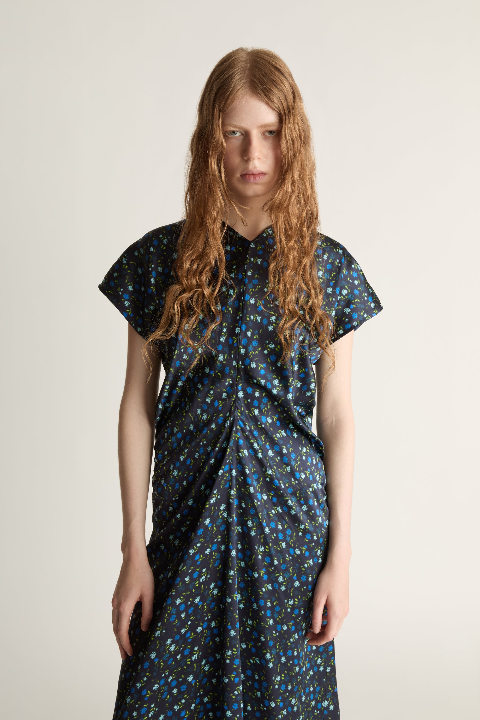 Woman wearing a long, patterned blue dress on a plain background