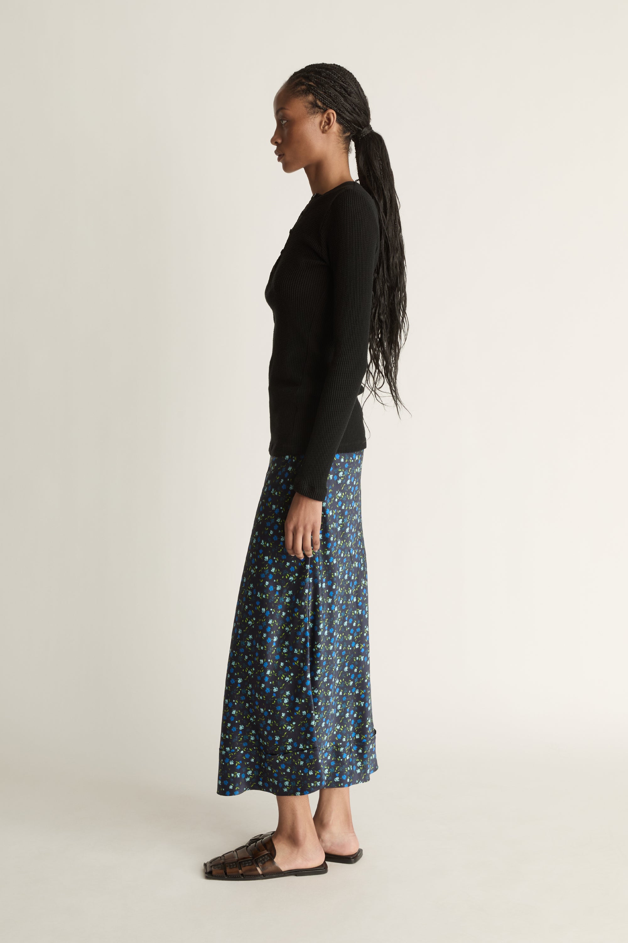 Woman wearing a black long-sleeve top and patterned skirt on a white background