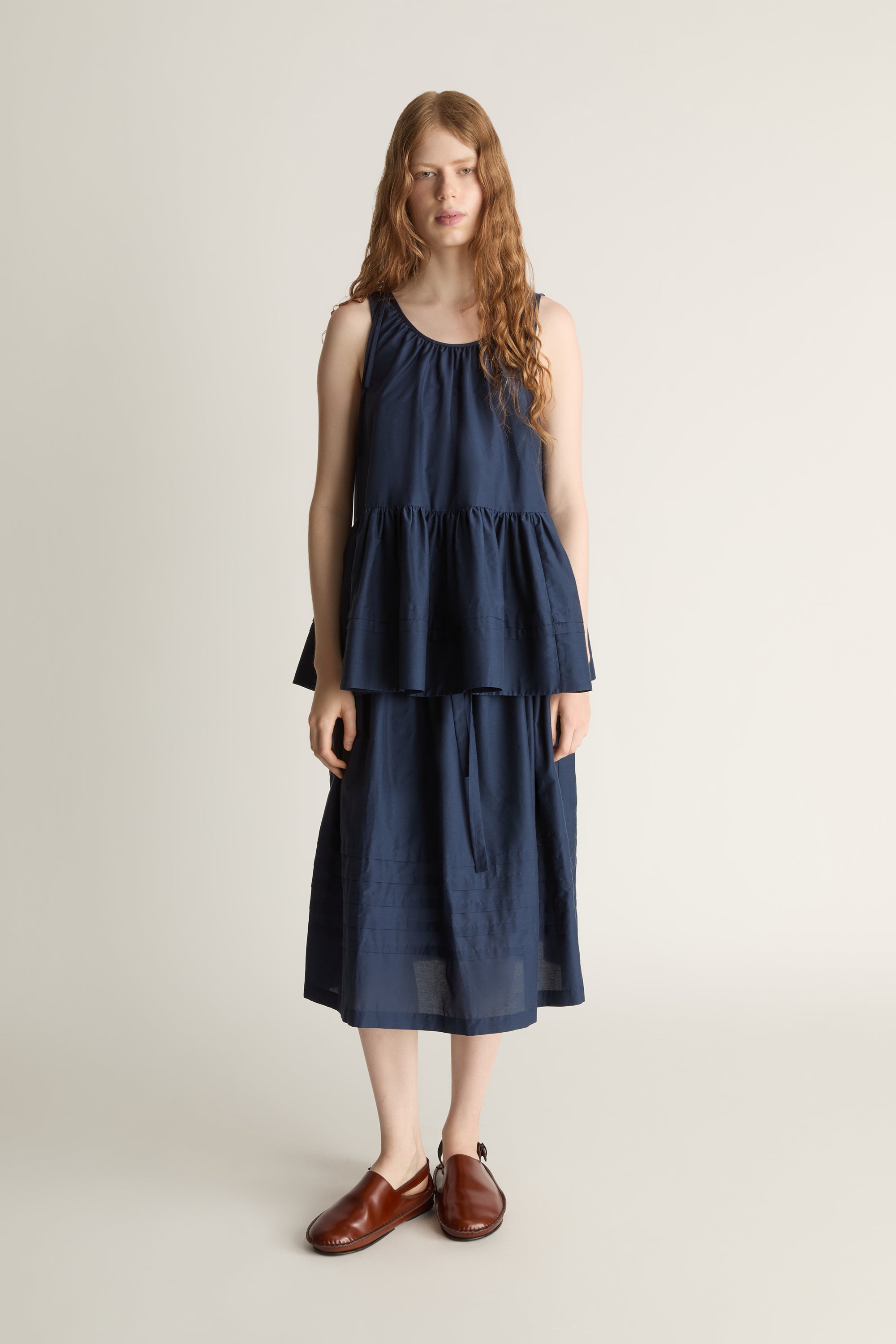 Woman wearing navy blue blouse with a gathered detail and a navy blue skirt on a white background