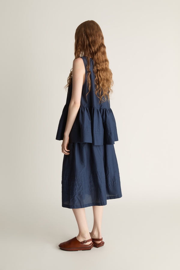 Woman wearing navy blue blouse with a gathered detail and a navy blue skirt on a white background