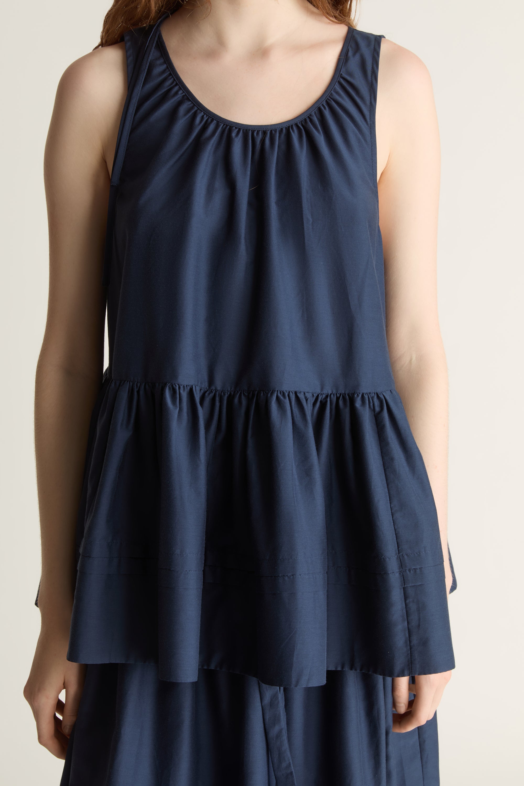 Woman wearing navy blue blouse with a gathered detail and a navy blue skirt on a white background