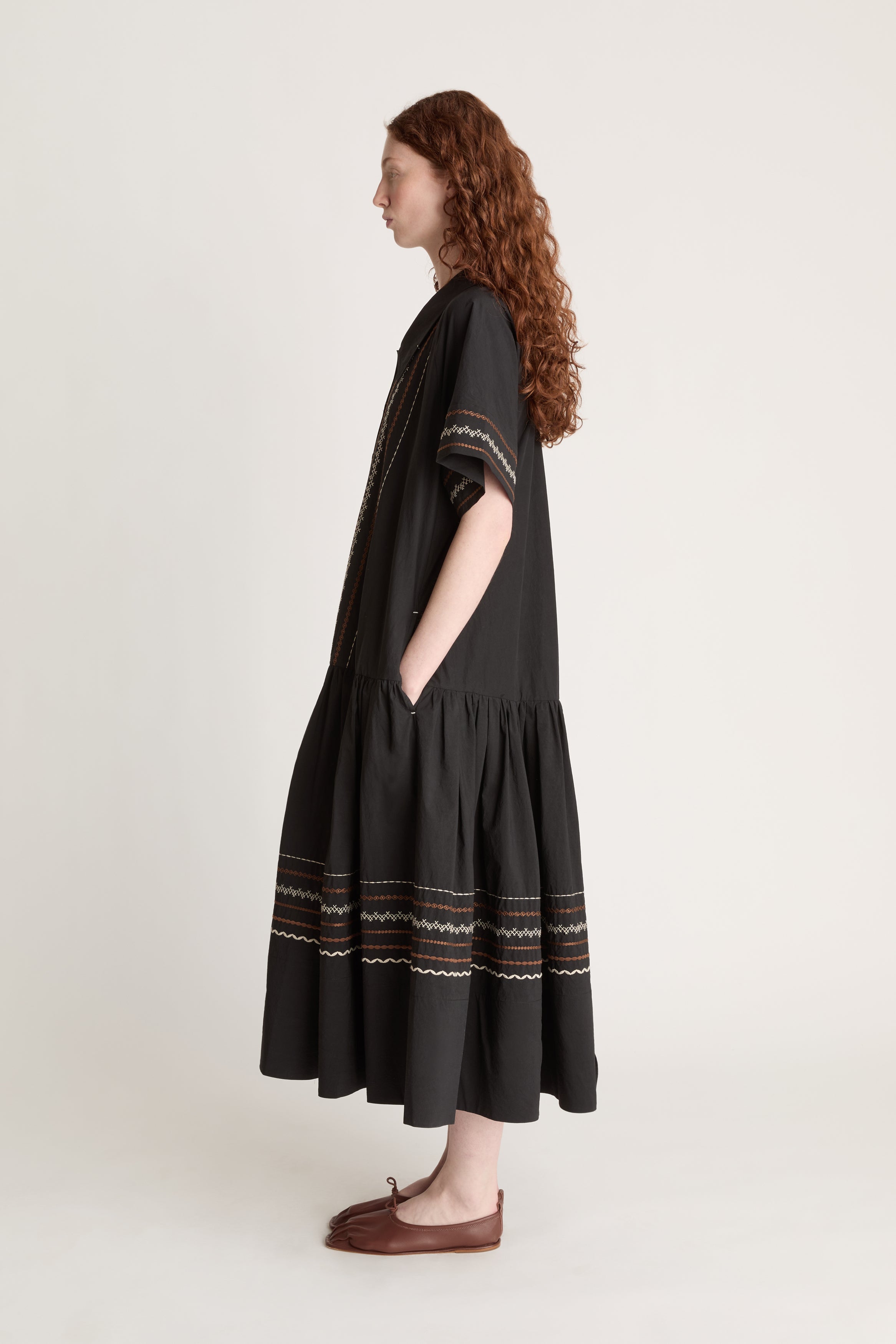 Woman wearing a black dress with patterned details on a white background