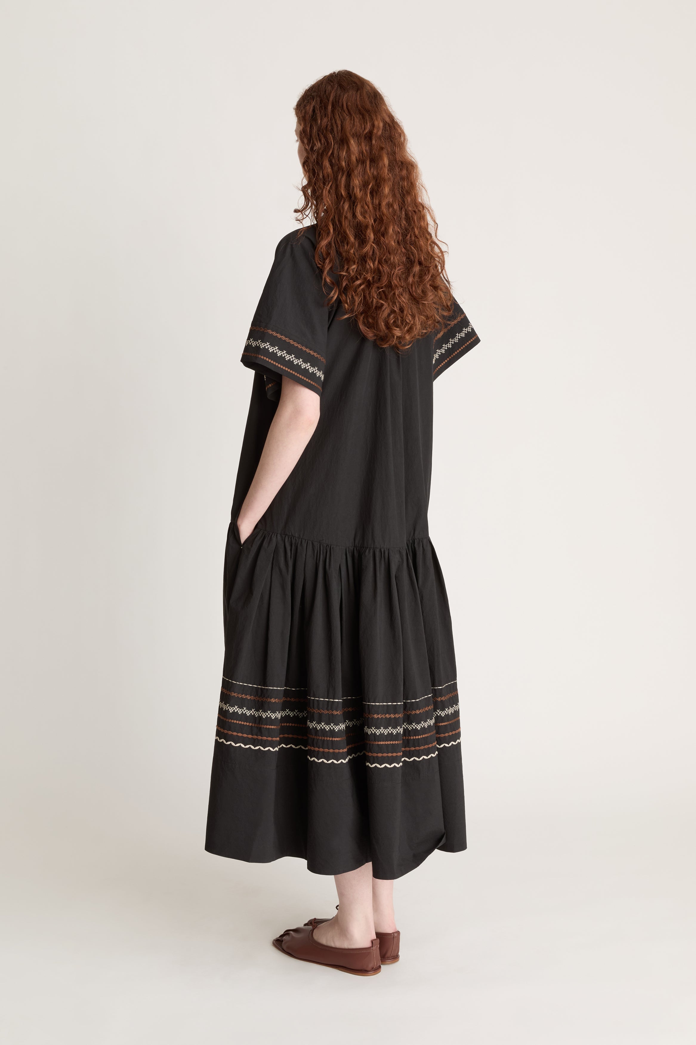 Woman wearing a black dress with patterned details on a white background