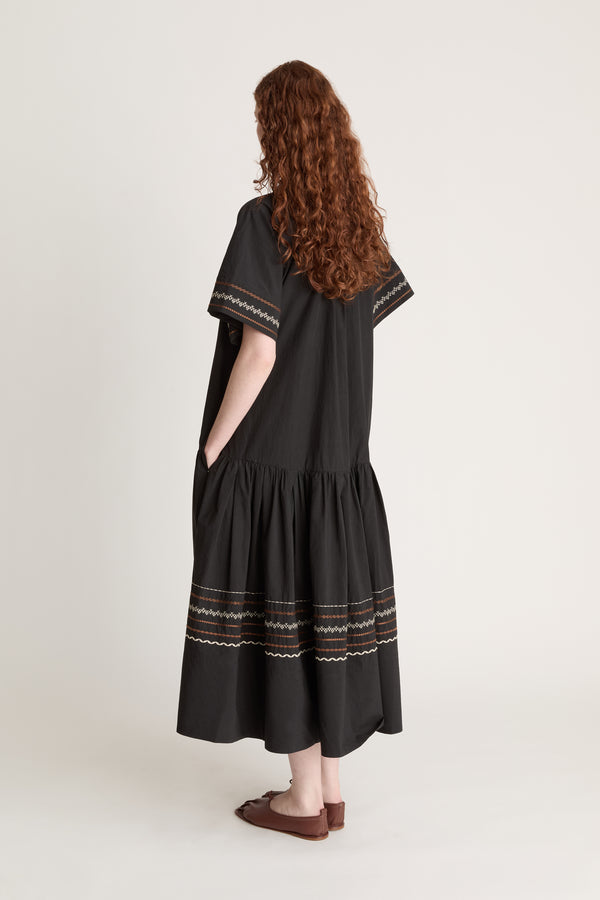 Woman wearing a black dress with patterned details on a white background