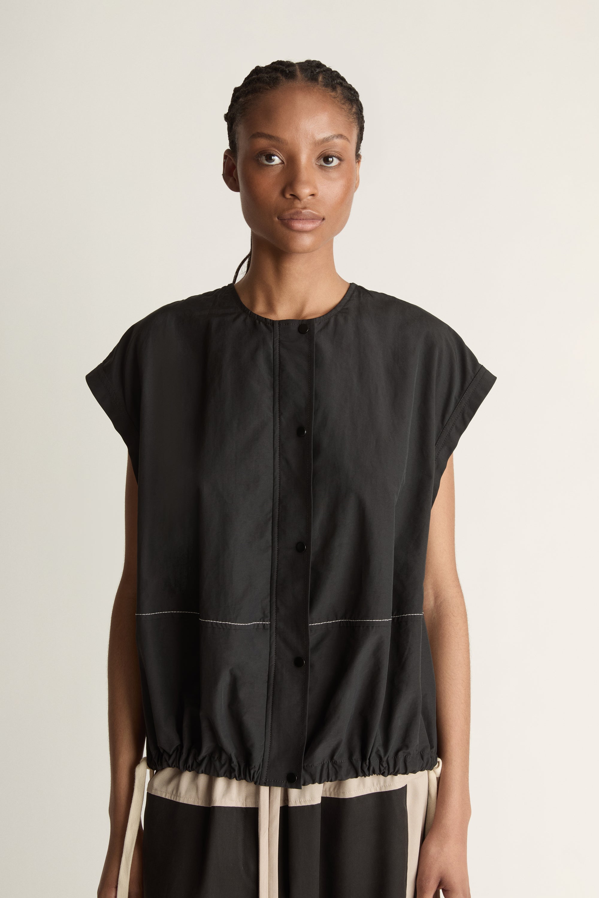 Woman wearing a black sleeveless top against a plain background