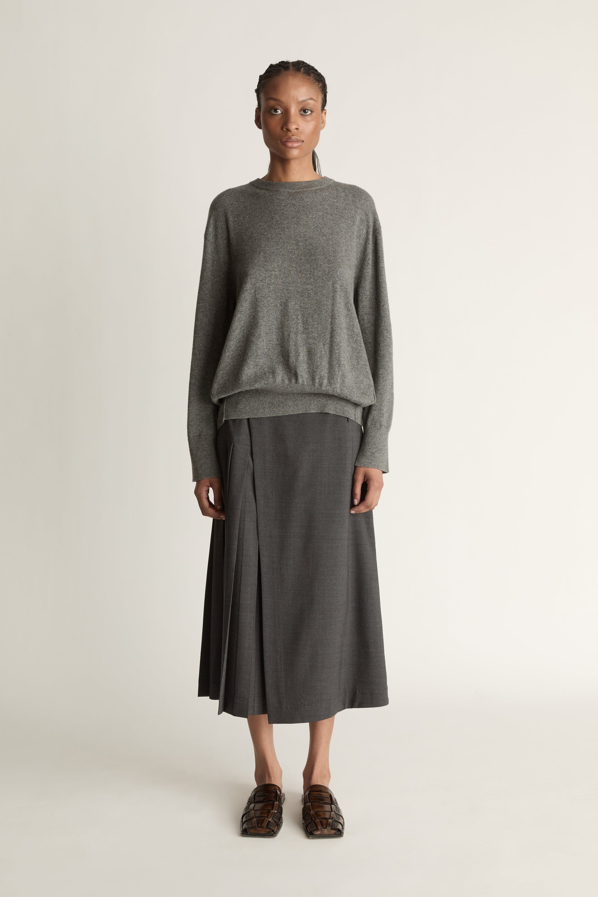 Woman wearing a gray sweater and skirt on a white background