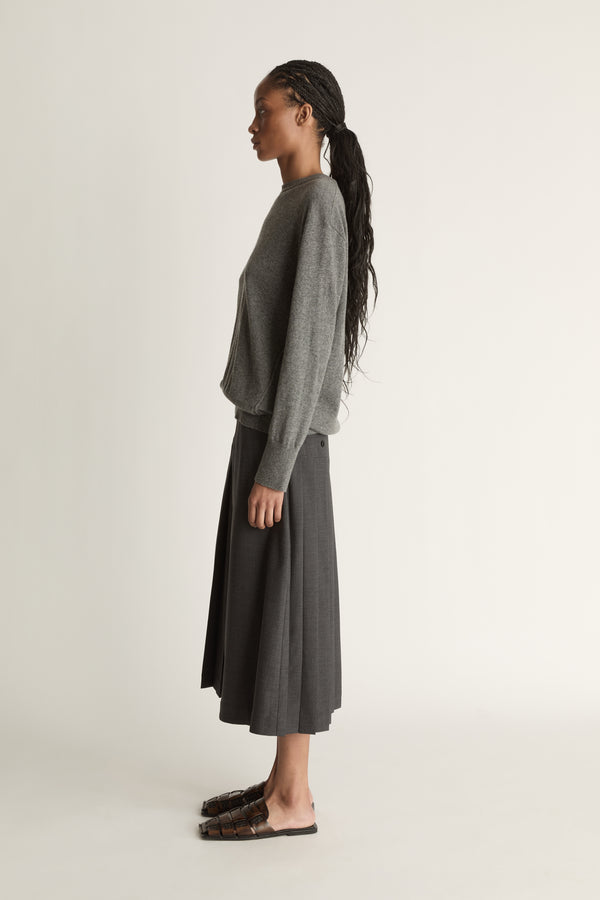 Woman wearing a gray sweater and dark gray skirt on a white background