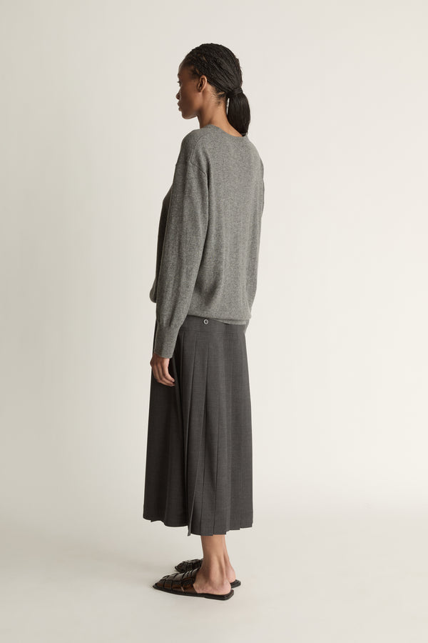 Woman wearing a gray sweater and dark gray skirt on a white background