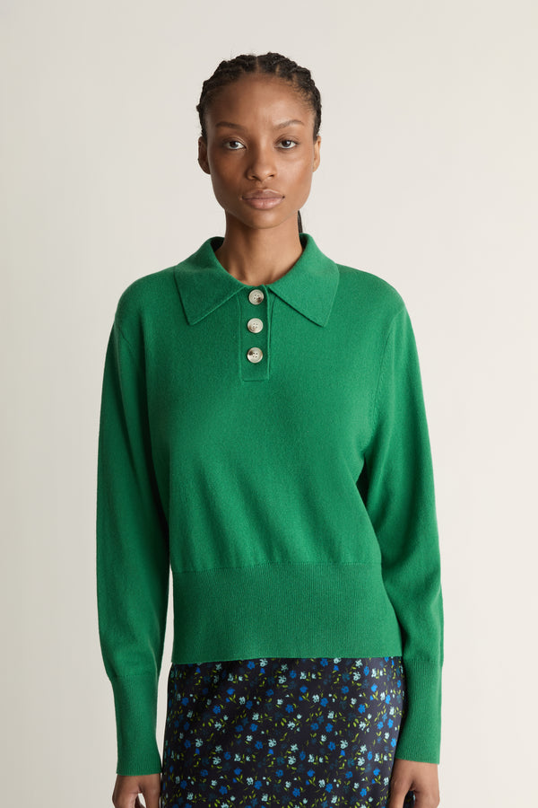 Woman wearing a green sweater and patterned skirt on a white background