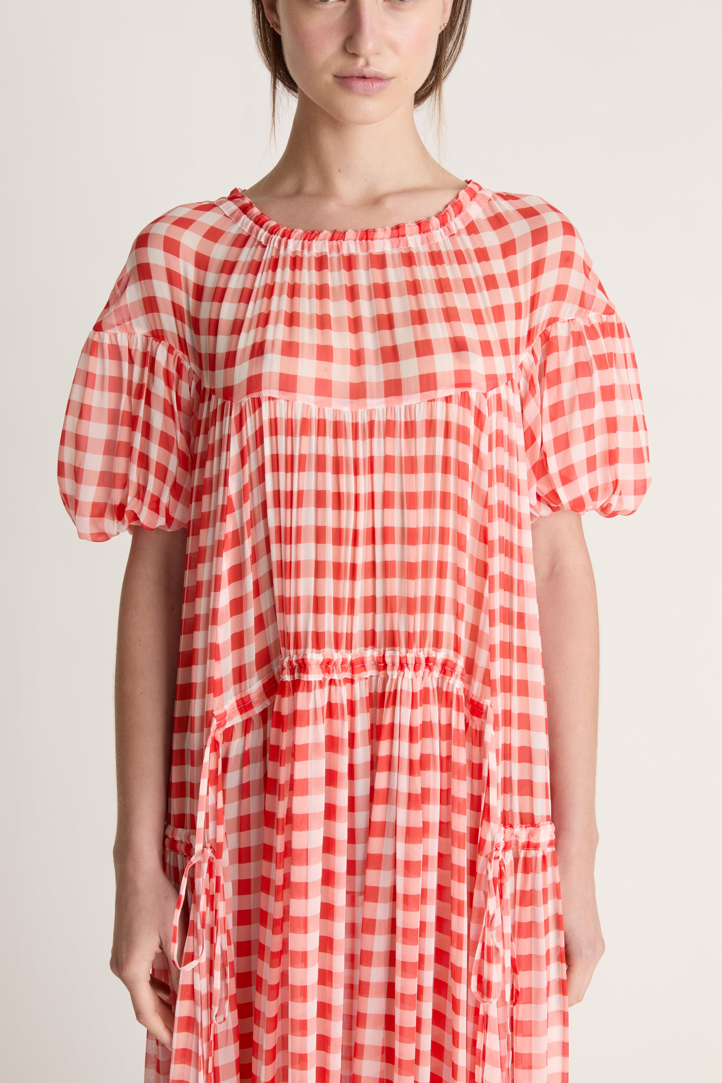 Red and white checkered dress worn by a person on a plain background