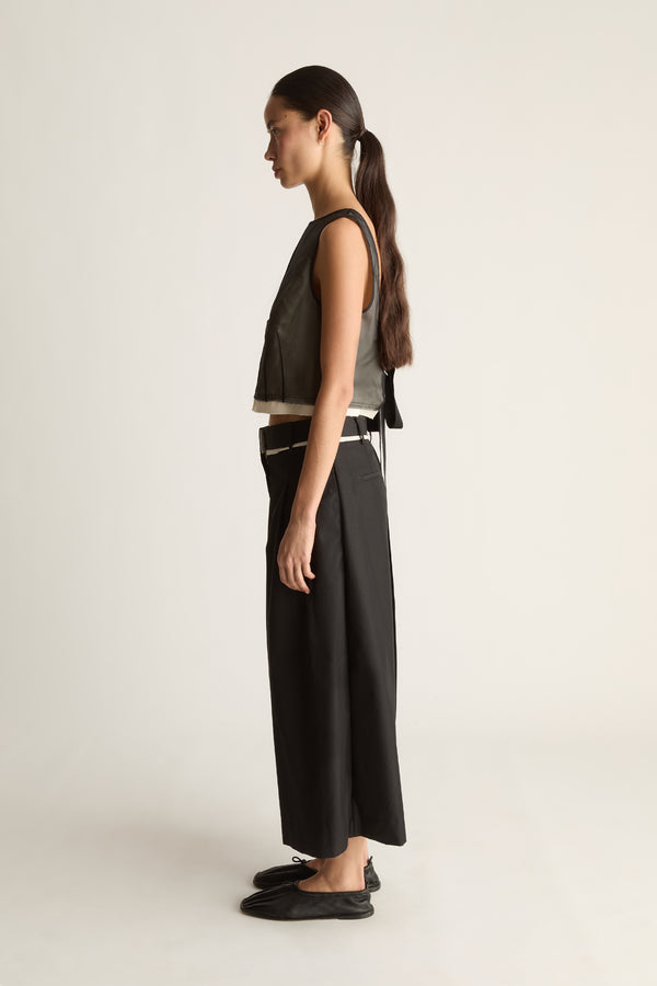 Side view of black wide-leg cropped pants with a pleated front and a hem ending above the ankle.