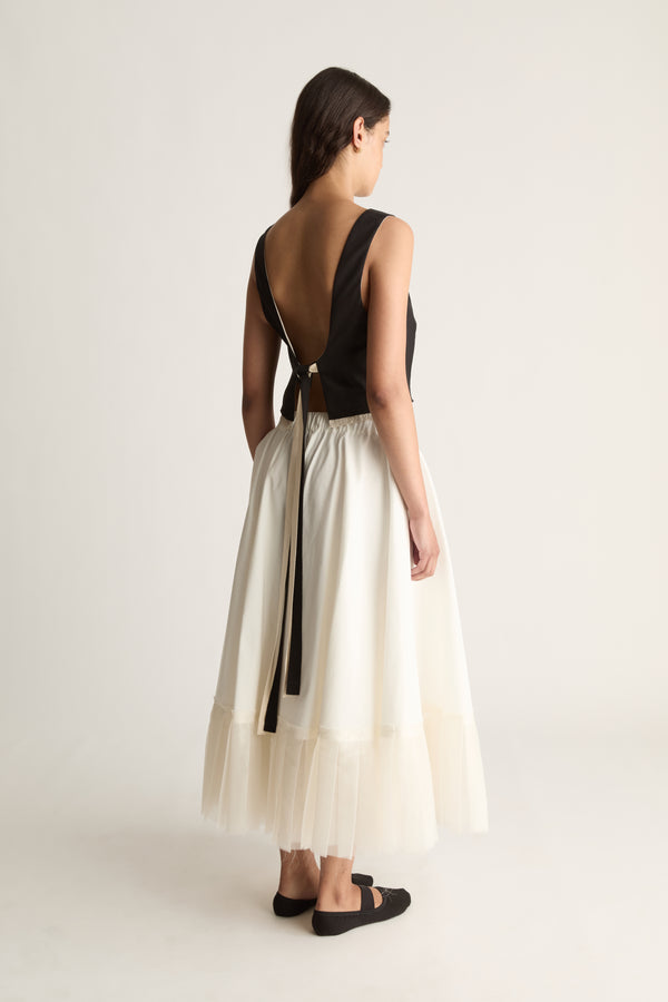 Back view of a cropped black top with a deep open back and long black ties hanging from the waist.
