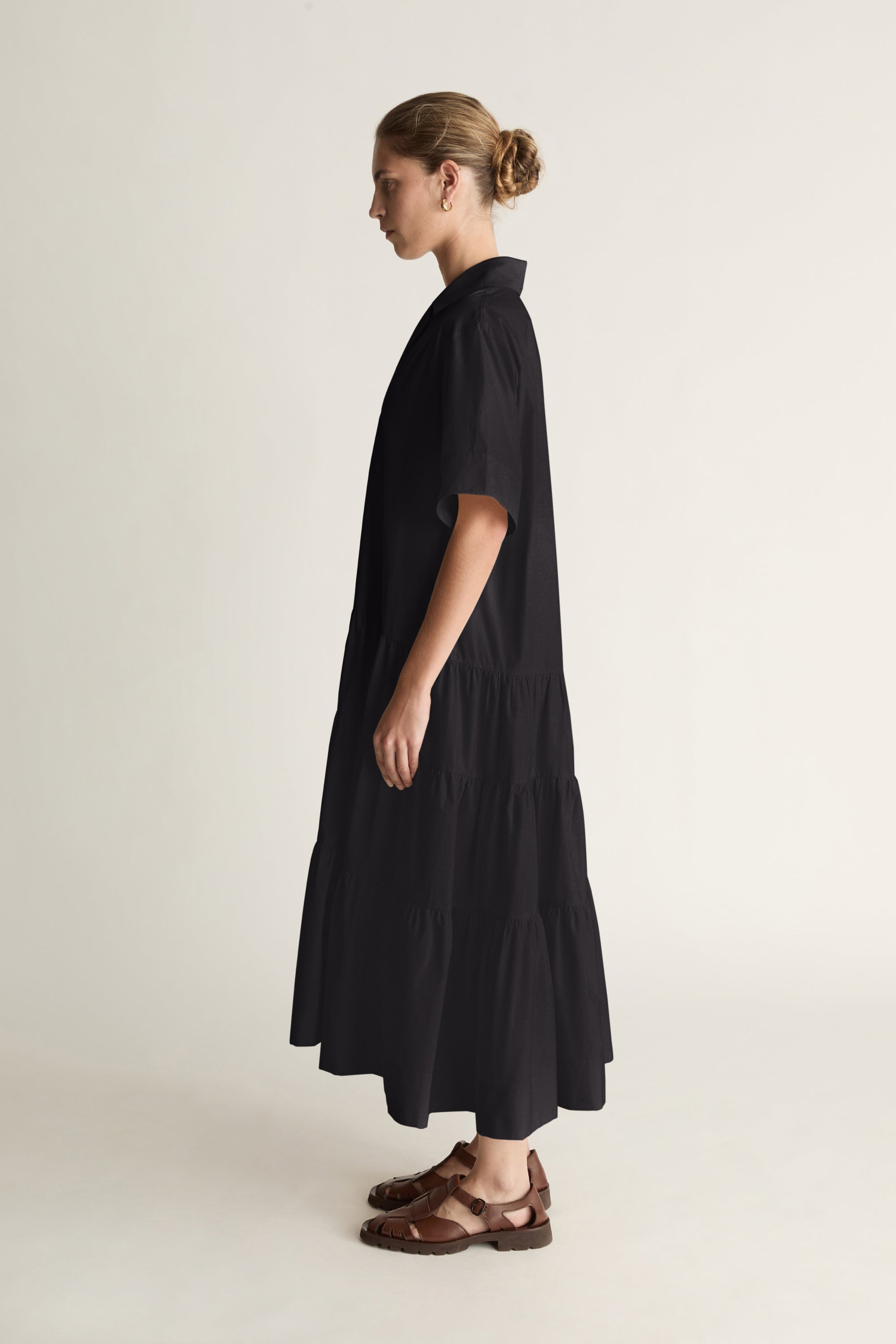 Woman wearing a black dress standing against a plain background