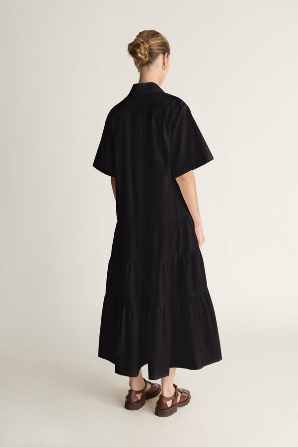 Person wearing a black dress standing against a white background