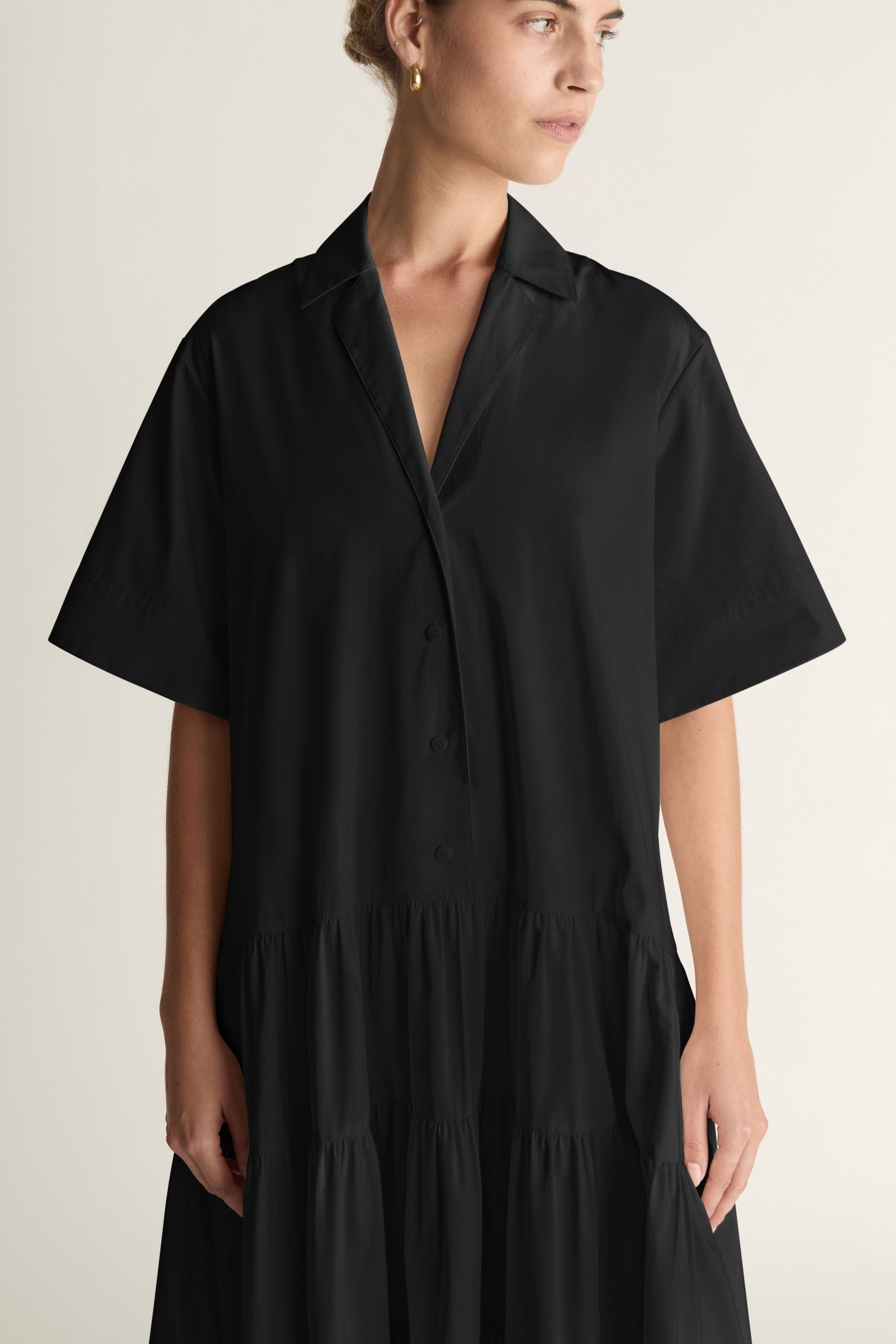 Person wearing a black dress standing against a white background