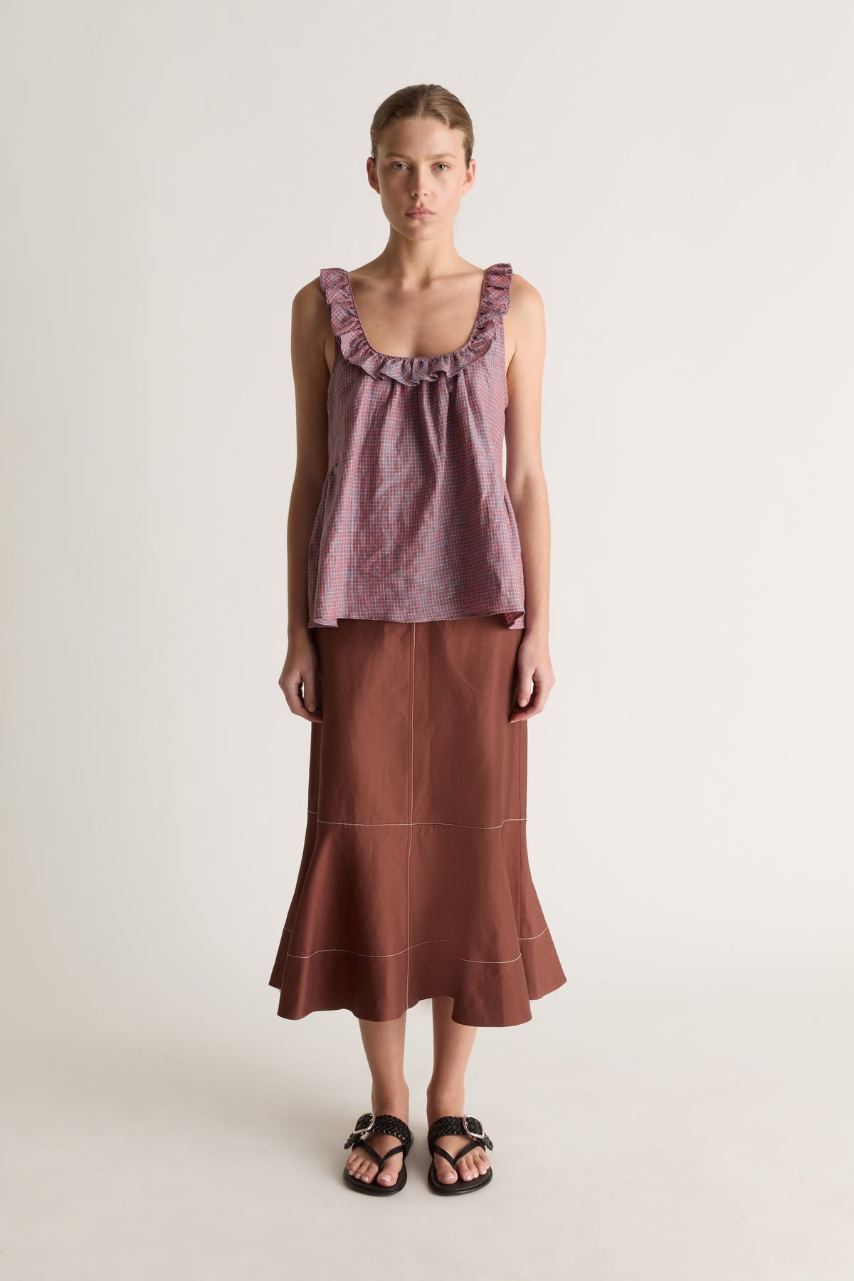 Front view of a woman wearing a plum check cami top with a brown flared midi skirt against a white studio background