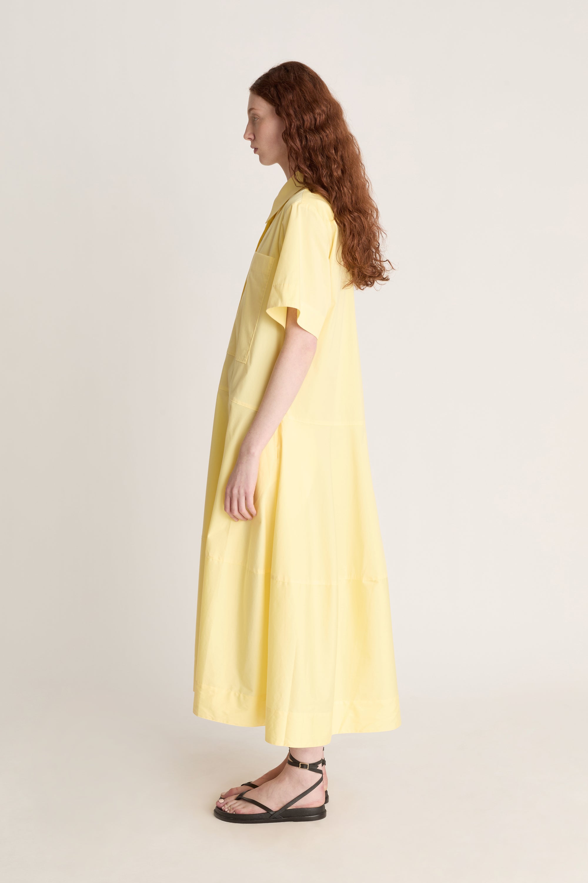Woman wearing a yellow shirt dress against a plain background