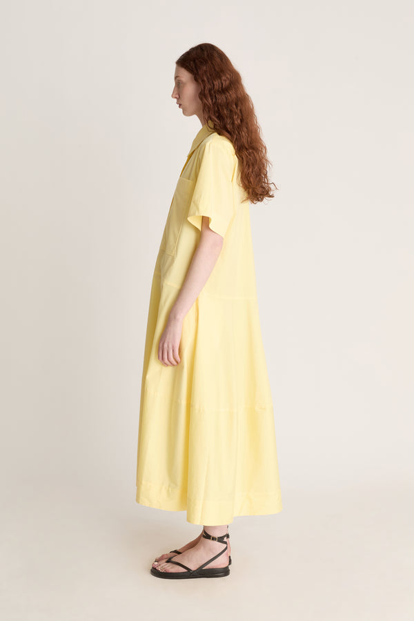 Woman wearing a yellow shirt dress against a plain background