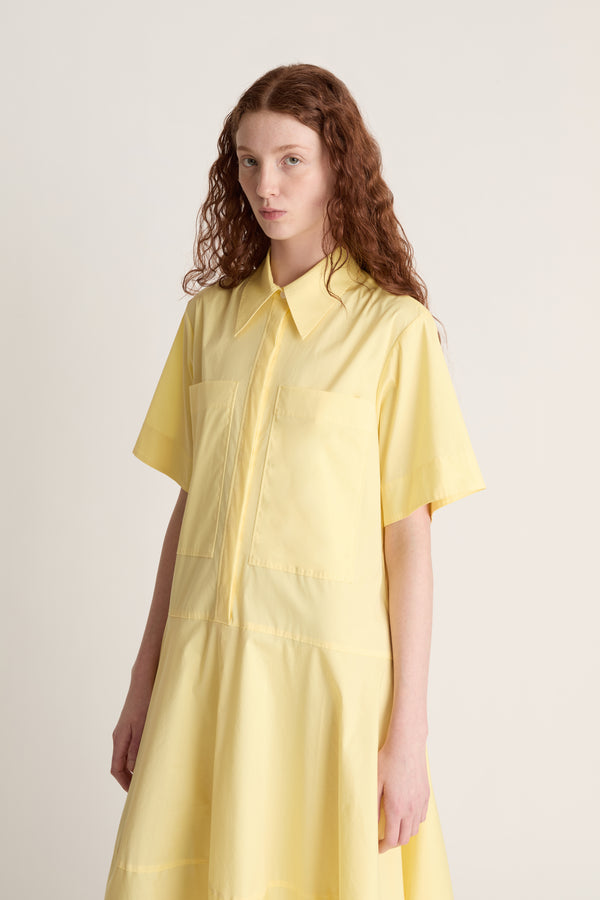 Woman wearing a yellow shirt dress against a plain background