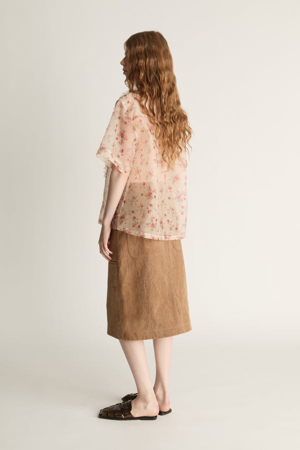 Person wearing a floral blouse and brown skirt on a white background
