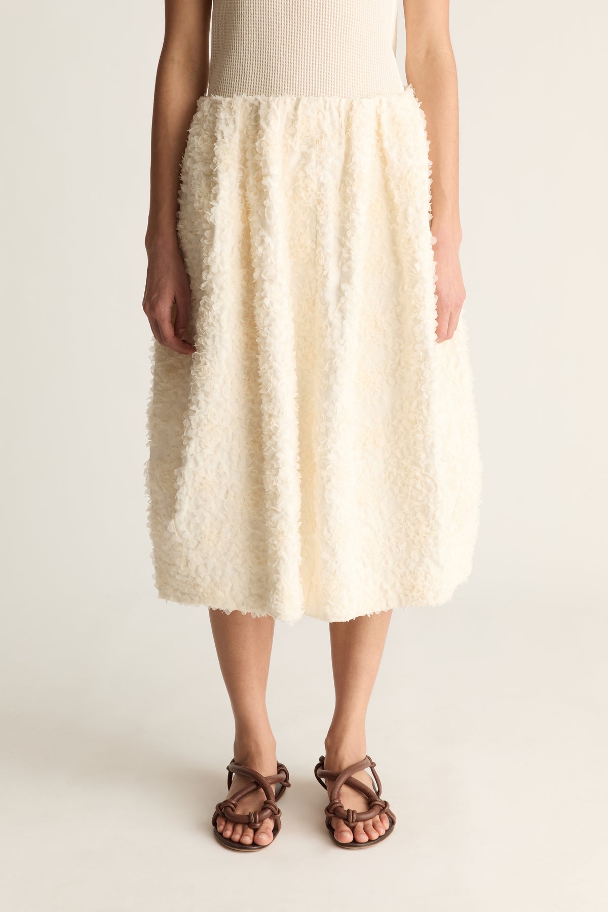 Close-up of a cream tufted cocoon midi skirt with gathered waist and rounded hem