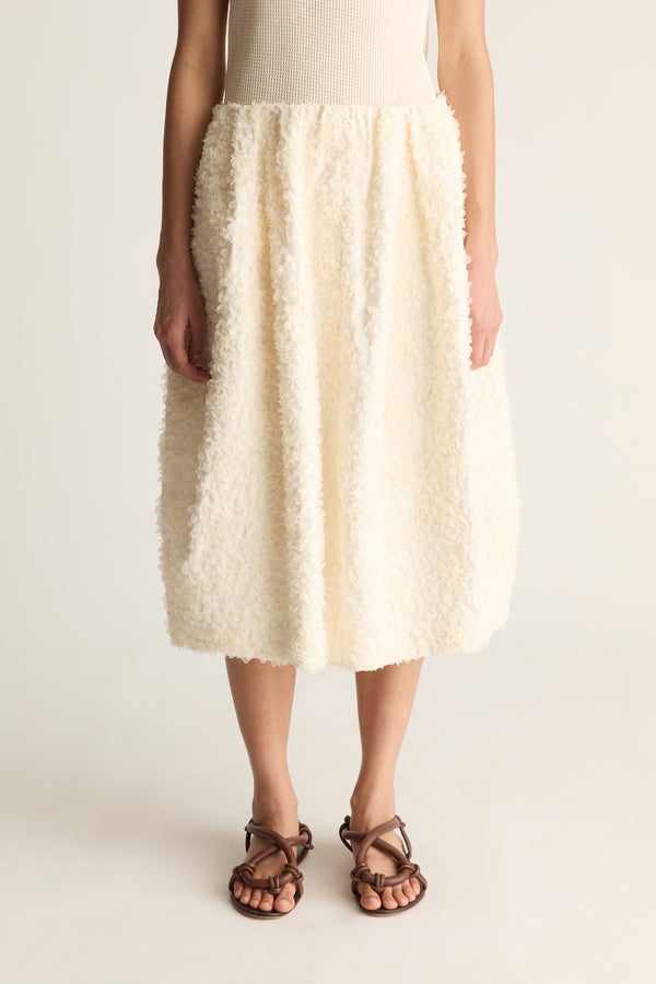 Close-up of a cream tufted cocoon midi skirt with gathered waist and rounded hem
