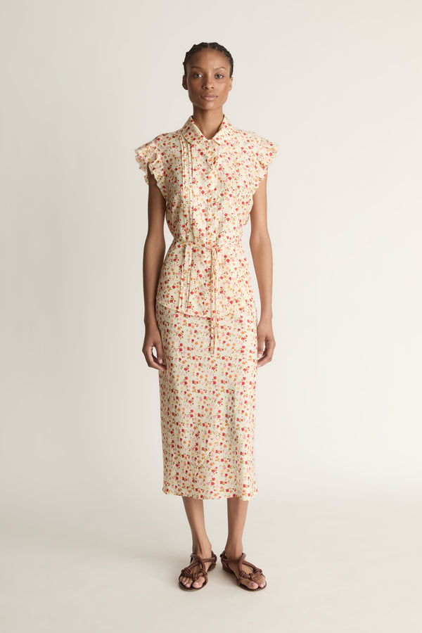 Woman wearing a floral blouse and skirt on a plain background