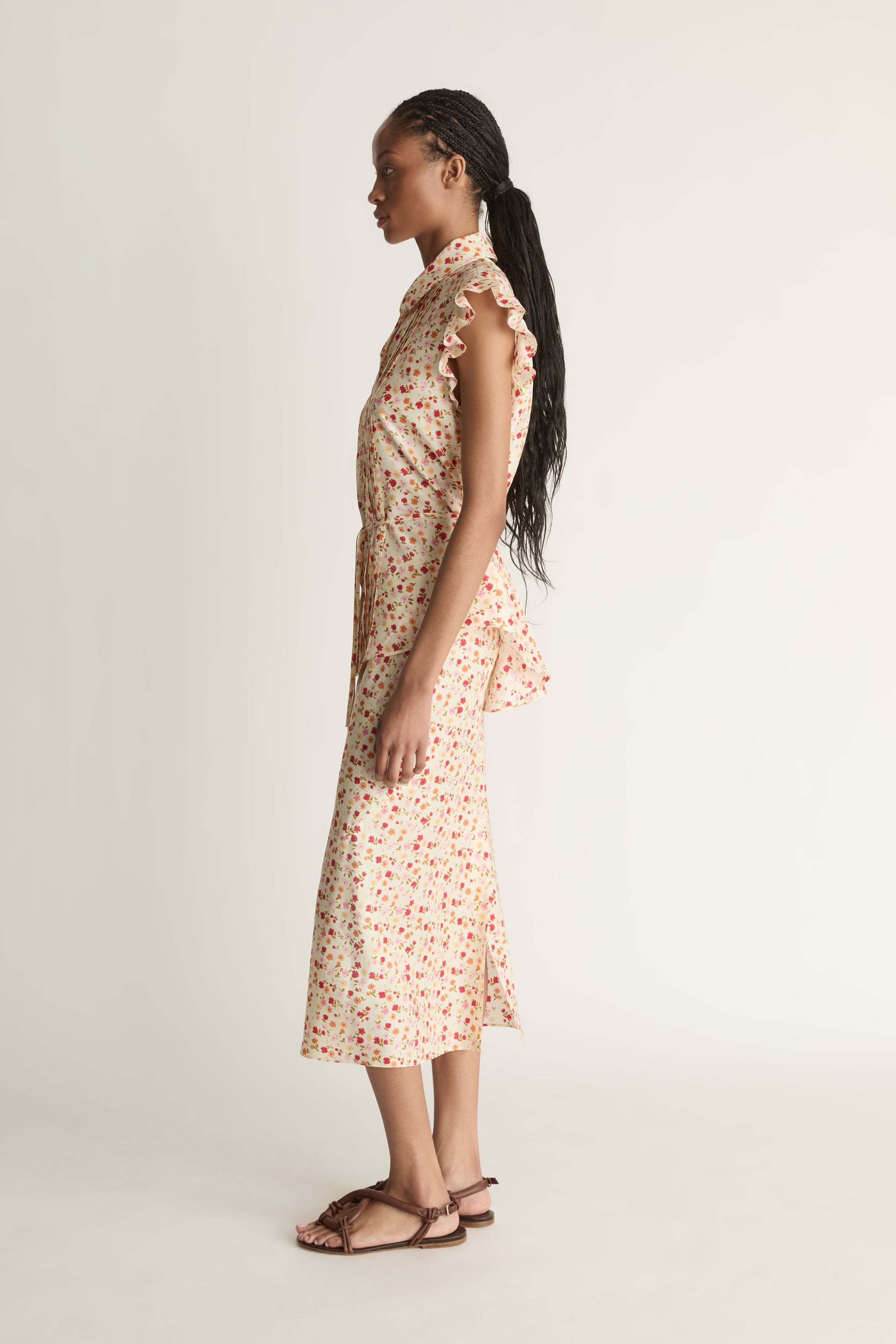 Woman wearing a floral blouse and skirt on a plain background